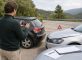 Conductor fotografiando los daños de dos coches tras un choque leve junto a documentos