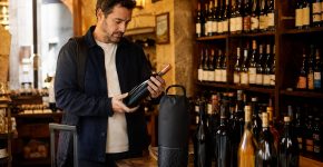 Viajero adulto escogiendo una botella regional junto a una funda protectora y una maleta